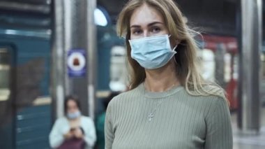 Maskeli kadın kalabalık metro istasyonunda yürüyor. Metroya giden kız covid 19