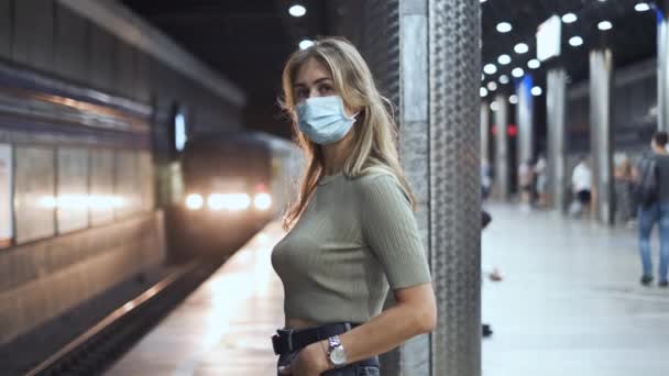 乘客们戴上口罩，等待地铁验尸。妇女站在站台上covid-19. — 图库视频影像