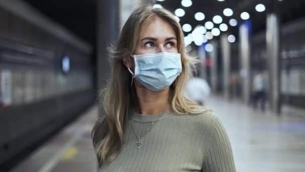地下鉄のコロナウイルスを待っているマスク旅客。女子スタンド駅covid-19. — ストック動画