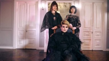 Kraliçe travestiler tahtta oturur travestiler lezbiyenler kadınlar. İnsanlar kameraya bakar.