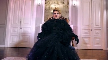 Travesti kadın hükümdar tahtta oturuyor. Transseksüel adam lgbt bak kamera.
