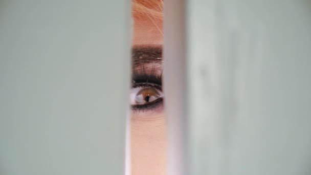 Цікаве око дівчина дивиться щілинні двері крупним планом. Носова людина шукала кімнату секретів . — стокове відео