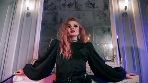 La sorcière rousse utilise une baguette magique pour Halloween. Femme gothique maquillage regarder caméra. — Video