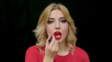 Portre kadını kırmızı ruj sürmüş. Yüzüne makyaj yapmış. Sarışın, makyaj dudağı sür..