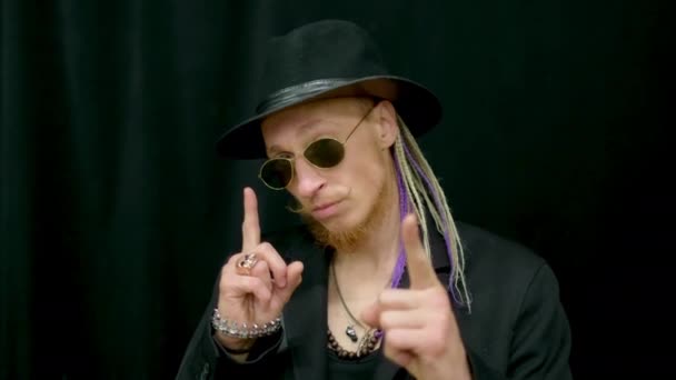 Dreadlocks hipster looking at camera gesturing hands. Punk man in sunglasses. — Stock Video