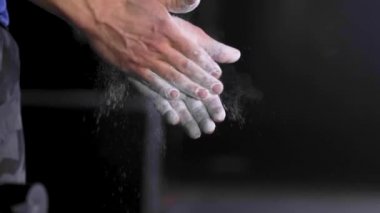 Sporcu magnezyum tozu el çırpıyor. Spor salonu tebeşiri önleme çabası kapağı.
