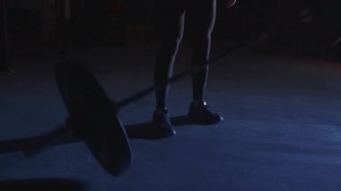 Kadın sporcu dolu spor malzemelerini bırakıyor. Halter bir kenara atılıyor.