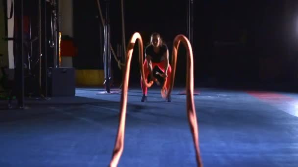 Wanita olahragawan melakukan latihan bertarung dengan tali yang berat. Gelombang pertempuran tali. — Stok Video
