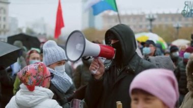 Maskeli protestocu megafonla konuşma yapıyor. Kızgın Rus aktivist..