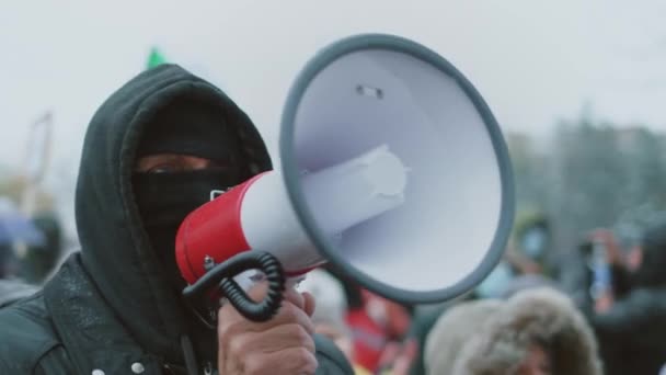 Анонимный российский протестующий выступает с речью на громкоговорителе. Беспорядки в городе. — стоковое видео
