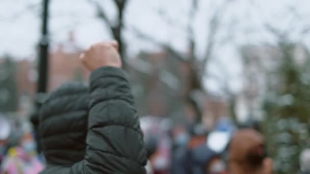 La foule protestataire agressive réclame justice. Homme adulte se tient avec poing levé. — Video