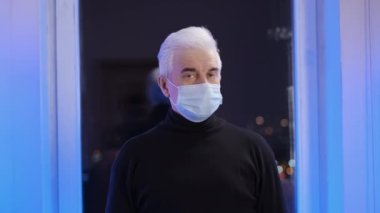 Yüz maskeli yaşlı hasta kameraya bakıyor. Corona Virüsü Hastalığı.
