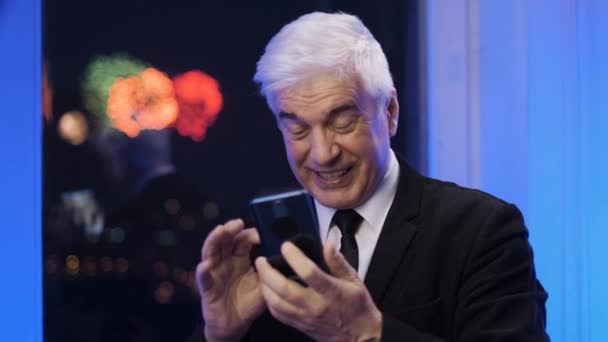 Happy European retired businessman has mobile phone conversation under fireworks — Stock Video