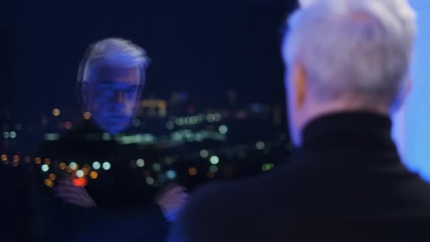 Insane old retired man in sweater looks at reflection in window. Mad thoughts. — Stock Video