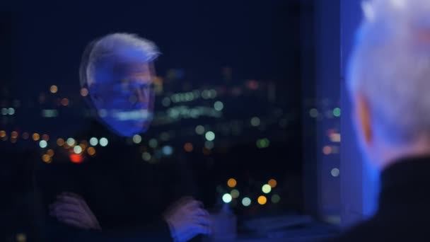 Божевільний старший сіро-волохатий бізнесмен в рулонній голові дивиться на відображення дзеркала вікна — стокове відео