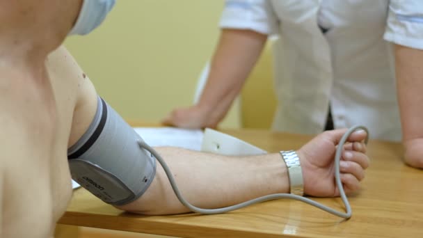 Uomo nudo ottiene la sua pressione sanguigna misurata con sfigmomanometro durante il controllo — Video Stock
