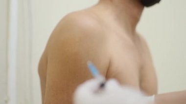 Pandemik doktor aşı ilacı enjekte eder. Hastaların kollarını dezenfekte eder.