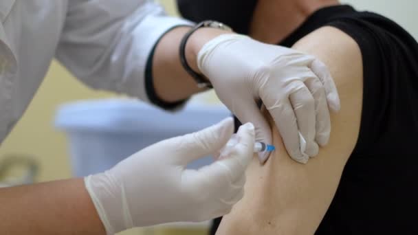 Médico en mascarilla inserta jeringa e inyecta vacuna contra la gripe contra el coronavirus. — Vídeos de Stock
