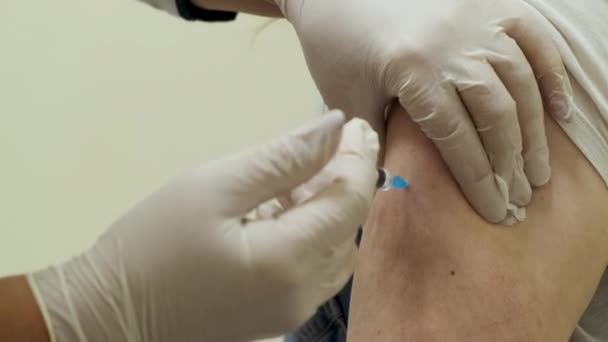 Medyk w masce do twarzy wkłada strzykawkę i wstrzykuje szczepionkę przeciw koronawirusowi.. — Wideo stockowe