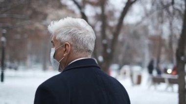 Kışlık bahçede yürüyüş yapan gri saçlı beyefendi. Kapalı alan 19 numara..
