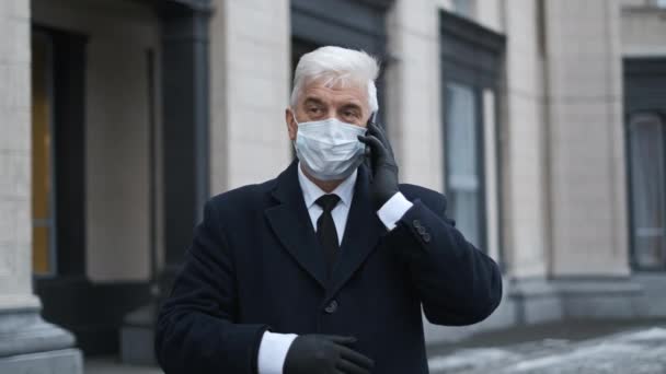 Gentleman en gants noirs et manteau avec masque visage parler sur smartphone sur la rue — Video