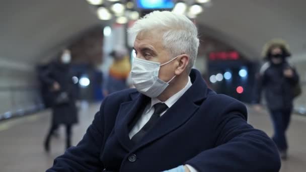 Yer altı istasyon peronu tecrit altında. Eldivenli maskeli yaşlı adam bekliyor.. — Stok video