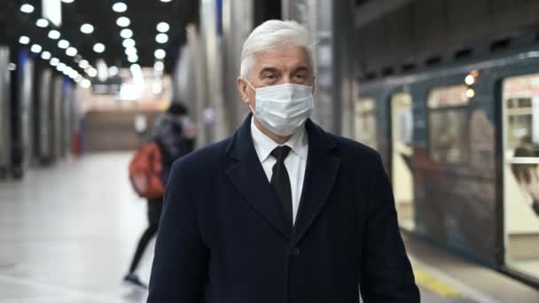 Stylish businessman in black coat and face mask walks on underground station. — Stock Video