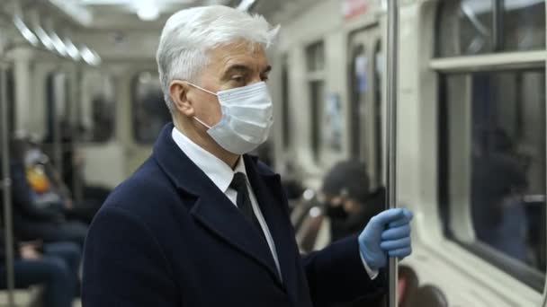 Hombre enmascarado en el vagón del metro sostiene la barandilla mientras está de pie. Subte en encierro. — Vídeo de stock