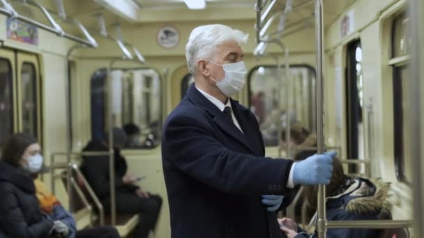Elegante caballero mayor en máscara y guantes se para en vagón de tren subterráneo — Vídeo de stock