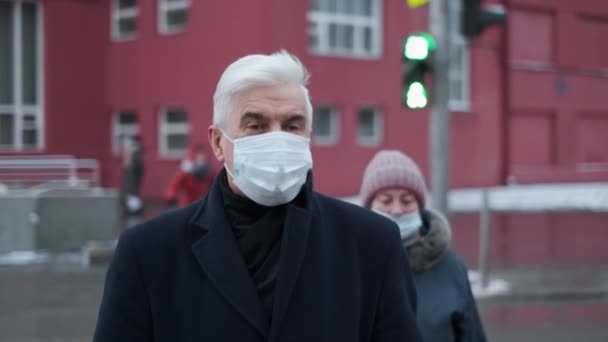 Zsúfolt városi zebrán, a járványban. Idős, maszkos üzletember sétál. — Stock videók