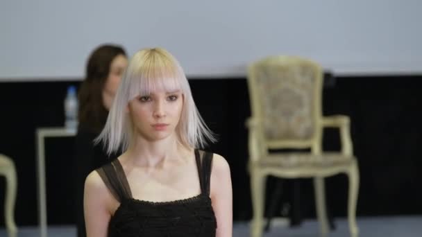 Girl with white albino hair moving on runway catwalk podium. Female model defile — Stock Video