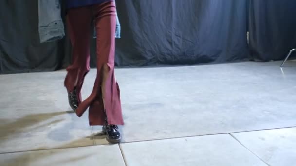 Γυναικείο μοντέλο σε σκισμένο κόκκινο τζιν και βαριές μπότες βόλτες σε διάδρομο podium catwalk. — Αρχείο Βίντεο