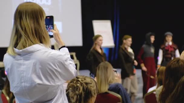 Visionneuse avec téléphone dans les mains enregistrement défilé défilé fashion week posant. — Video