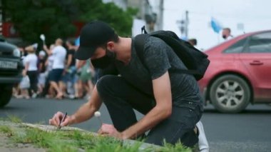 Gösteri kalabalığında erkek protestocu işaret levhasıyla el ele verdi.