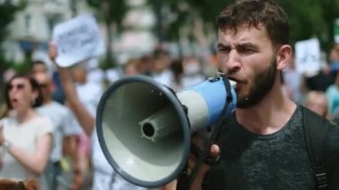 Megafonla yürüyüp konuşan öfkeli bir protestocu. Megafon eylemcisiyle bağırıyor.