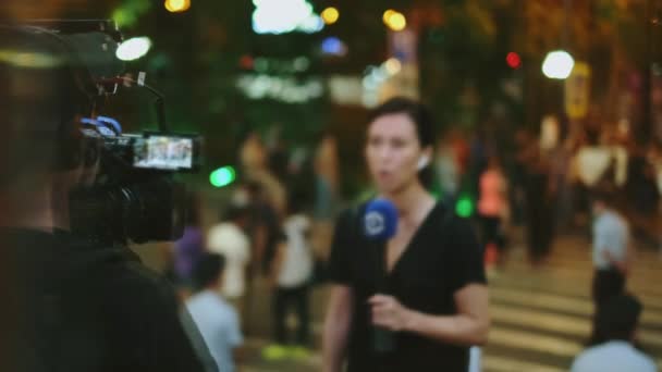 Reproduktorka novinářky je natáčena kameramanem na pozadí rally protesty. — Stock video