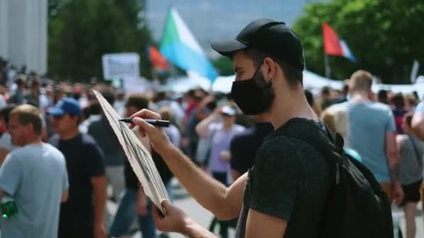 Demonstran pria menggambar tanda banner di tangan dengan penanda di kerumunan kerusuhan.. — Stok Video