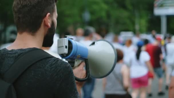 Ung skäggig manlig protestant med megafon bullhorn marscher och samtal på gatan — Stockvideo