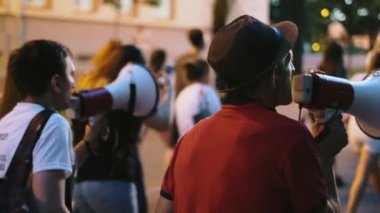 Megafon ve megafonlarla sokaklarda yürüyen sivil hakları eylemcileri protesto ediyorlar.