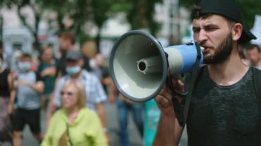 Megafonla yürüyüp konuşan öfkeli bir protestocu. Megafon eylemcisiyle bağırıyor.