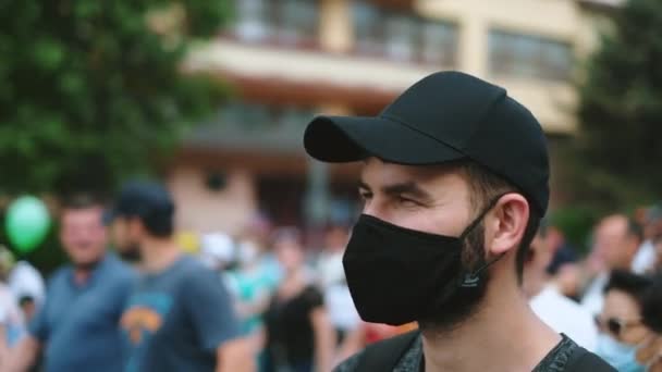 Portrait d'un militant rebelle masculin masqué marchant dans une foule de manifestants. — Video