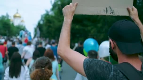 Демонстрант в маске с плакатом под пандемическими ограничениями. — стоковое видео