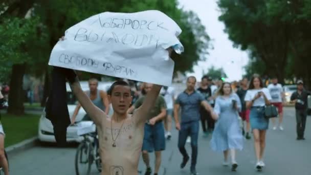 Mladý protestant s holým trupem a prapory pochoduje v davu nepokojů. — Stock video