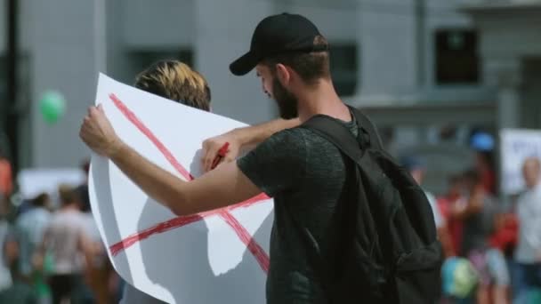 Skäggiga proteststrejkaktivister drar upp strejkplakat. Upplopp tecken, affisch. — Stockvideo