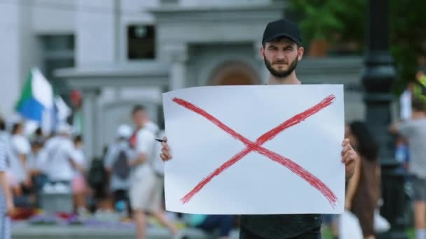 Manifestant politique gars avec bannière pancarte se tient sur l'action de rassemblement anti-émeute bondé. — Video