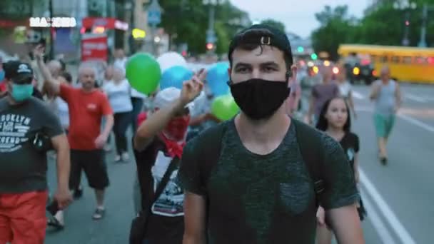 Manifestante hombre en máscara facial covid caminando en restricciones multitud de gente de la oposición. — Vídeo de stock
