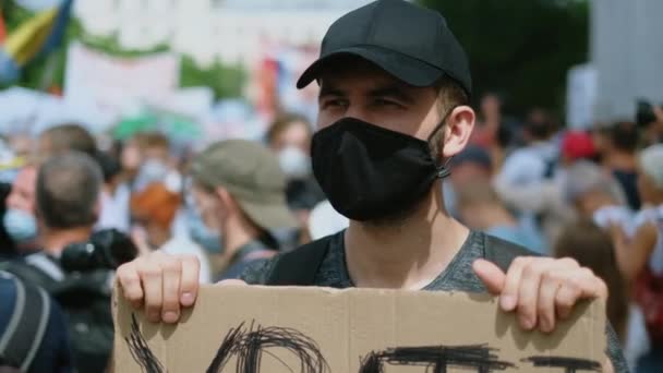 Активист политического митинга в маске с плакатом против коронавируса. — стоковое видео