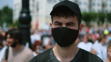 Coronavirus 'lu isimsiz protestocunun portresi kalabalık yürüyüşünde duruyor.
