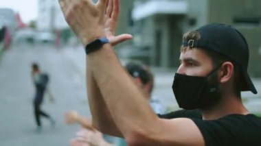 Yüz maskesi takan isyancı eylemci kalabalıkta el çırpıyor..