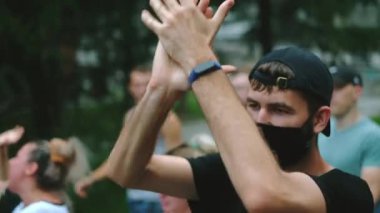 Kilit altındaki siyasi muhalefet mitinginde maskeli erkek el çırpıyor